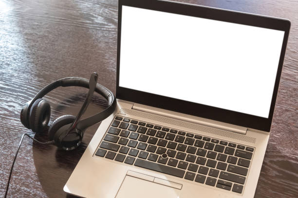 istock Headset on a laptop, blank white screen, wooden table background, 1369690682