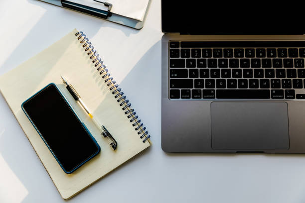 istock Overhead view of workspace with laptop, smartphone, notepad. 1369692903