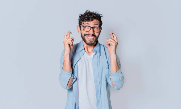 istock Happy man making a wish, latin guy crossing his fingers making a wish 1369694316
