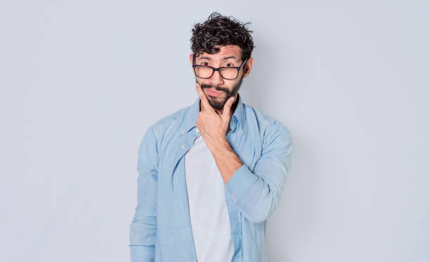 istock Man rubbing his beard with an expression of doubt, Image of a handsome bearded man with an expression of doubt 1369694387