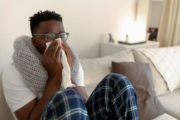 istock Sick black man blowing his nose in a handkerchief. 1369696700