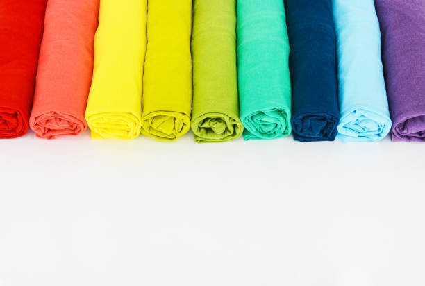 stack of colorful t-shirts rolled up on white background, copy space
