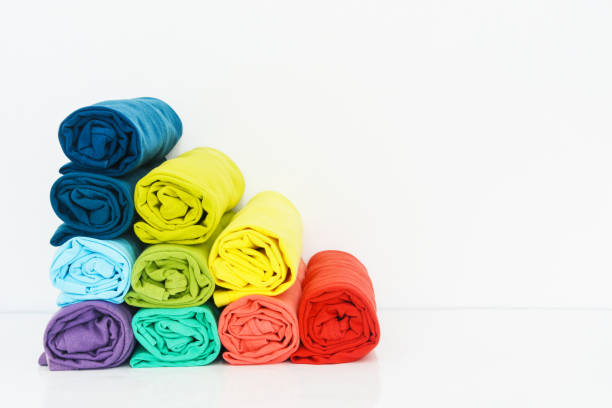 istock stack of colorful t-shirts rolled up on white background, copy space 1369696790