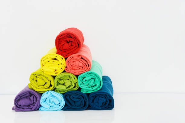 istock stack of colorful t-shirts rolled up on white background, copy space 1369696798