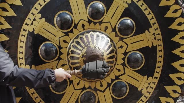tourist person hitting Clangs a Giant oriental gong Bell at Thai temple