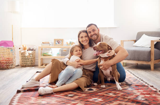 ganzkörperaufnahme einer jungen familie, die mit ihrem hund zu hause auf dem wohnzimmerboden sitzt - six animals fotos stock-fotos und bilder