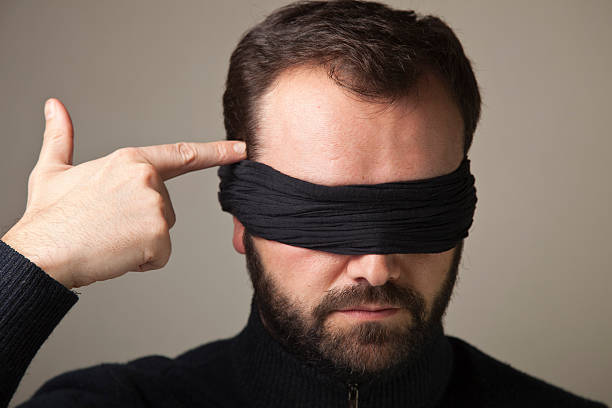 Blindfolded man aiming at his head with hand Blindfolded man aiming at his head with his hand as if it was a gun head shoot stock pictures, royalty-free photos & images