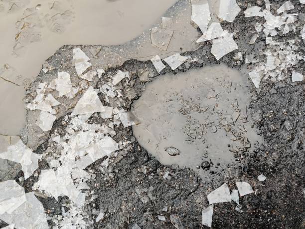 istock Broken asphalt. Pit on the road in the winter, surrounded by ice. 1369699480