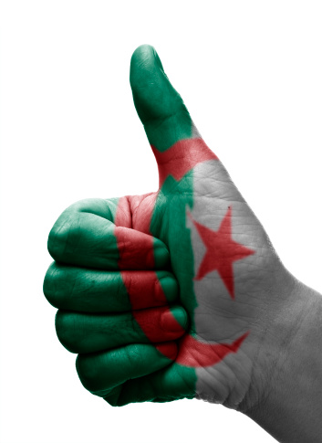 Human hand doing the thumbs up sign isolated on white with the algerian flag painted on it. You can also use it as a thumbs down just rotating it 180º