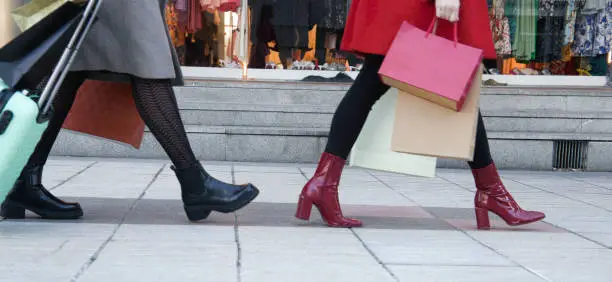 feet of women walking in line with shopping bags