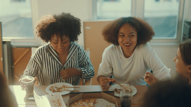 teenage friends of various nationalities join in for a simple dinner. - pizza eating african descent lunch imagens e fotografias de stock