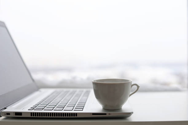 xícara de café e laptop na mesa contra a janela, vista para a cidade de inverno - heat snow urban scene creativity - fotografias e filmes do acervo