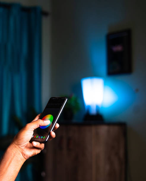 istock Close up shot unrecognizable person controling smart bulb using mobile phone at home - concept of technology, smart IOT devices, 1369703328