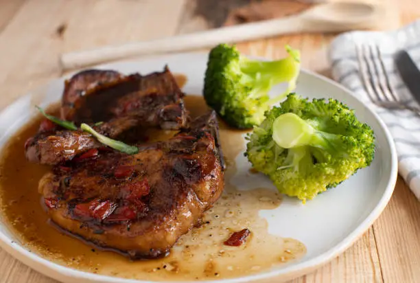 Plate with fresh and homemade braised pork chops. Cooked in a delicious brown sugar, garlic  sauce and served with broccoli. Ready to eat