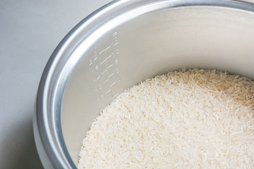 Close up shot of an unrecognizable woman filling a bowl with cooked rice in the kitchen  at home.