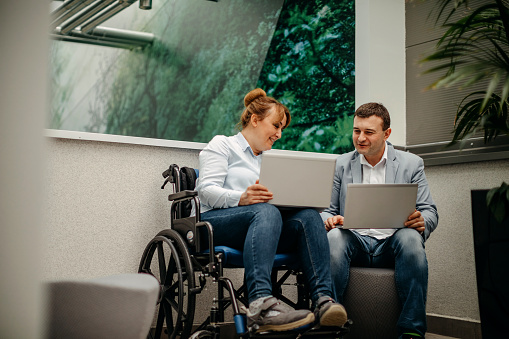 Taking a break with colleague in wheelchair using laptop