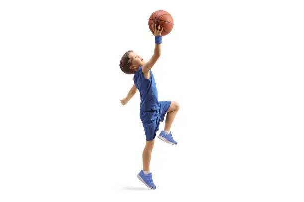 Photo of Full length profile shot of a boy in a blue jersey jumping with a basketball