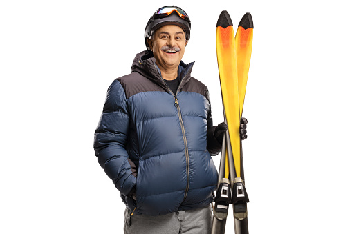 Mature man holding a pair of skis isolated on a white background