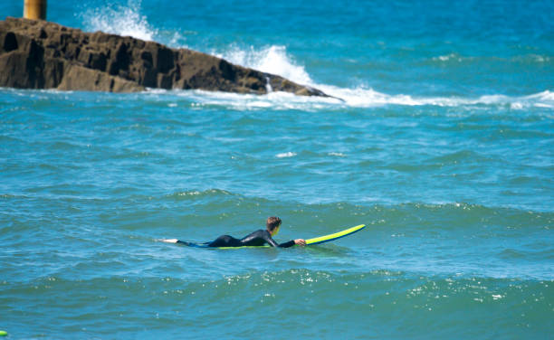 A young man on a surfboard enjoying his holidays in Cornwall.