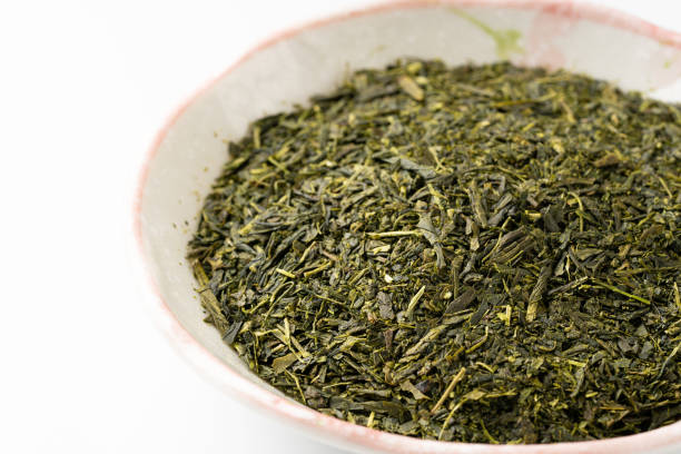istock Dried green tea leaves on white background 1369710526