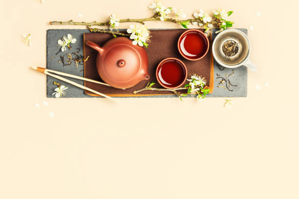 istock Asian Tea set on stone slate board, ceramic teapot, cups, dried tea and spring branches 1369710842