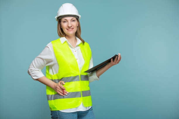 istock Professional engineer. A woman in a hardhat and bright jelly is using a tablet, on a blue background. Copy paste 1369711049
