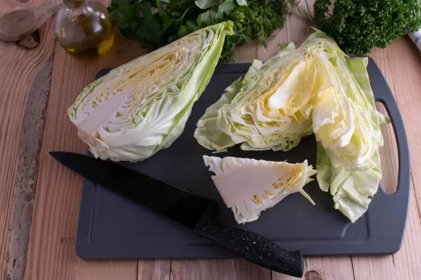 Cutting and chopping of fresh and raw white cabbage. Served with kitchen knife on a cutting board.