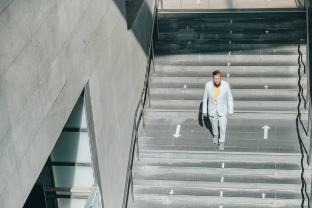 istock senior business man standing on stairs with direction arrows 1369712297