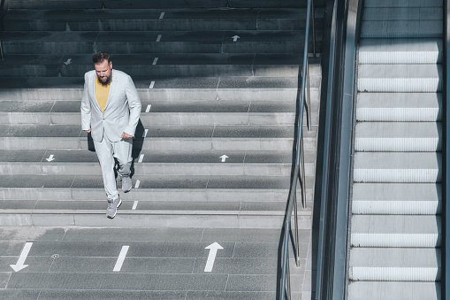 elegant bearded senior business man coming down stairs in city