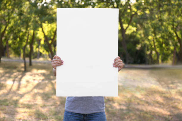istock Woman holding blank poster outdoors. Mockup for design 1369713849