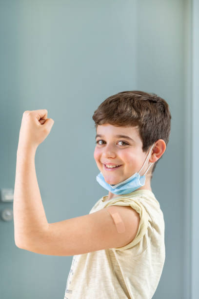 istock Happy smiling boy looking at camera showing proud vaccinated arm. 1369716435