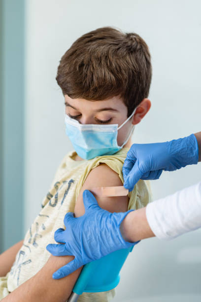 istock Nurse's hands with gloves put a band aid on a boy's arm after vaccination. 1369716500