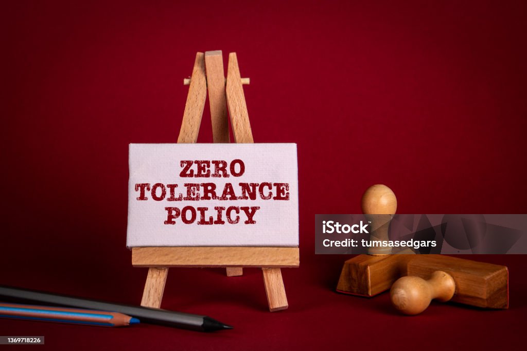 Zero Tolerance Policy. Miniature easel and wooden stamps on a bright red background Zero Tolerance Policy. Miniature easel and wooden stamps on a bright red background. Zero Stock Photo