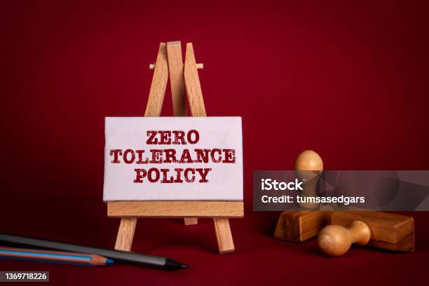 Zero Tolerance Policy Miniature Easel And Wooden Stamps On A Bright Red Background Stock Photo - Download Image Now