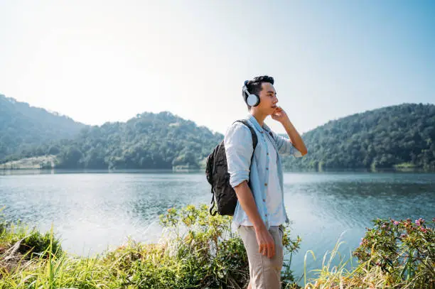 Photo of Young Asian man breathing fresh air with headphones in a forest