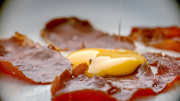 The egg is thrown into the Turkish pastrami in the hot pan.