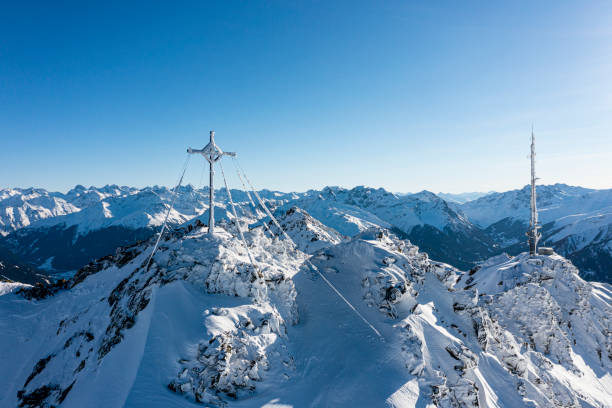 Frozen summit cross and a communication tower on top of a mountain. Vorarlberg, Montafon