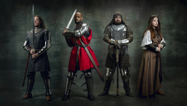 istock Heroes. Creative art collage with brutal serious medieval warriors or knights in war clothes with wounded faces holding shield, sword isolated over dark vintage background. 1369722416