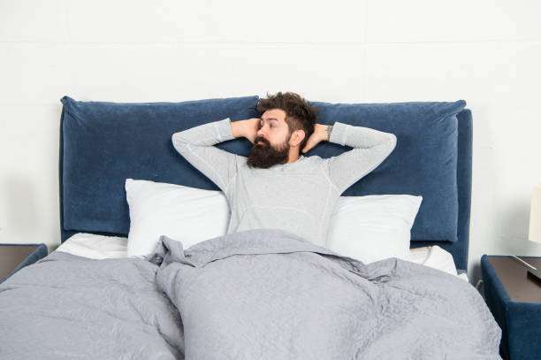 istock Drowsy guy being in bed awake after sleep, morning 1369722663