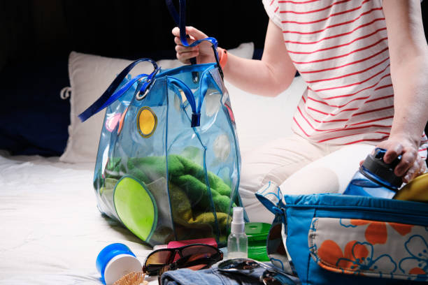 istock Woman is sitting on bed and packing beach bag 1369723588