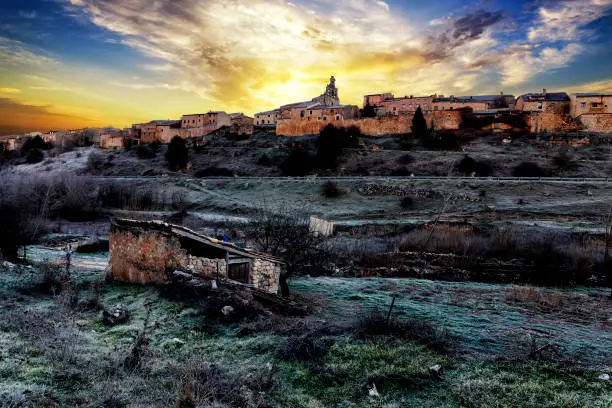 Frost in abandoned orchard and the historic medieval village of Maderuelo at dawn in winter. Segovia.