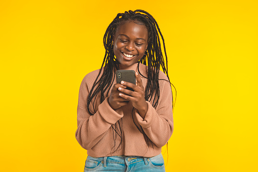 African teenager on yellow background with her smart phone