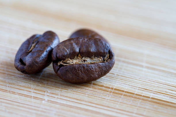 Roasted coffee beans in close-up on a wooden surface.