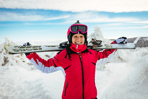 Portrait of happy woman in winter clothing wearing ski googles.