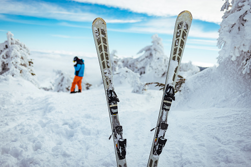 Pair of skis in snow. Skis standing in snow with winter mountains in background. Winter holiday vacation and skiing concept.