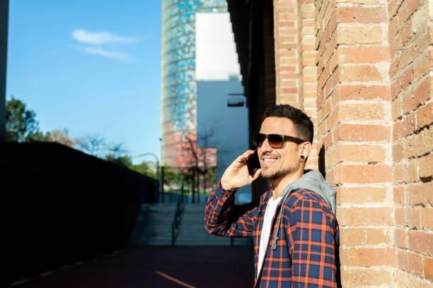 istock Young man smiling and talking on mobile phone outside 1369727895