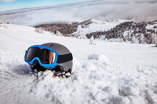 Ski helmet and ski goggles in the snow on top of the mountain.