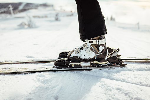 Legs of a professional skier at the time of relaxation on the ski slope. A winter sports concept with an adventurous guy on top of the mountain who is ready to ride down.
