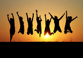 istock silhouette of friends jumping in sunset 136972823