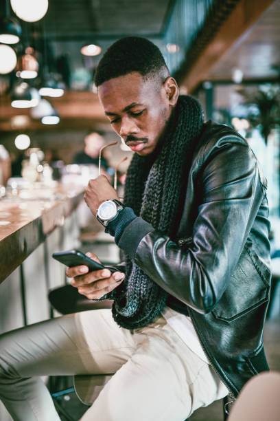 istock Elegant African Male Browsing Through Phone While Enjoying Drink On Bar Counter 1369730682
